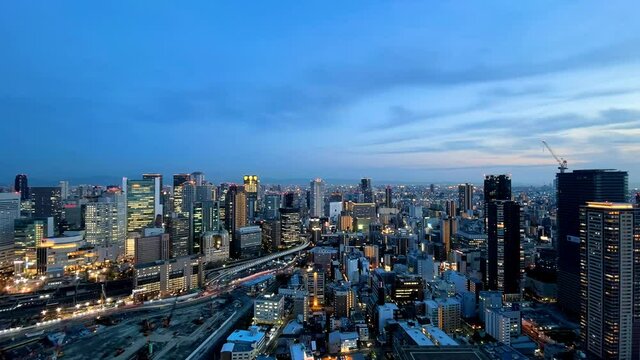 UMEDA, OSAKA, JAPAN : Aerial high angle sunset view of CITYSCAPE of OSAKA. View of buildings and street around Osaka and Umeda station. Wide view time lapse shot, dusk to night.