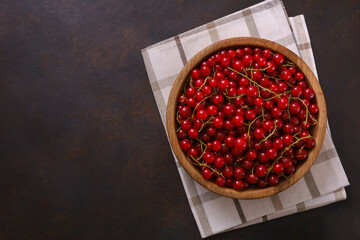 Fresh red currant in wooden bowl on dark table