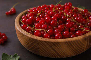 Fresh red currant in wooden bowl on dark table