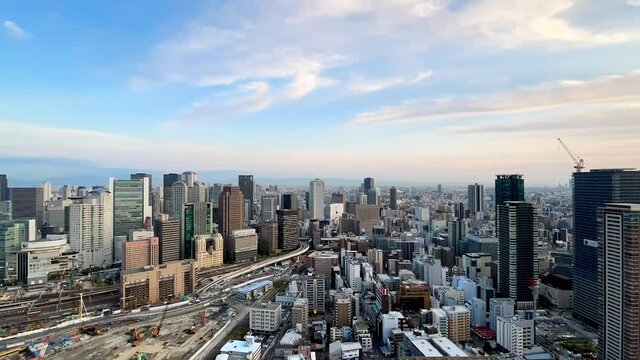 UMEDA, OSAKA, JAPAN : Aerial high angle sunset view of CITYSCAPE of OSAKA. View of buildings and street around Osaka and Umeda station. Wide view time lapse zoom in shot, dusk to night.