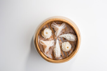 Chinese dim sum dumplings in bamboo basket isolated on white background