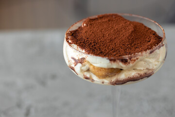 Tiramisu dessert in a glass on gray surface