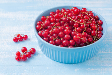 Fresh red currant in wooden bowl on dark table