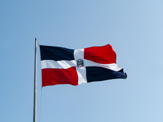 Fototapeta na wymiar The Dominican flags waving with blue sky in the background
