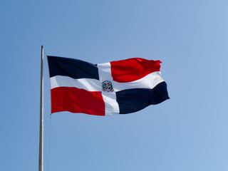 Fototapeta na wymiar The Dominican flags waving with blue sky in the background
