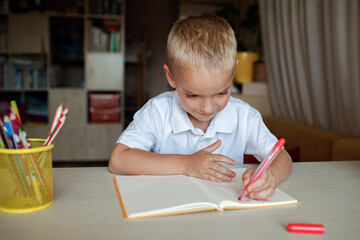 Happy left-handed boy writing in the paper book with his left hand, international left-hander day celebration, only lefties understand