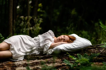Foto op Canvas A woman sleeps in the woods on a pillow. Healthy, sound sleep concept. Rest, relaxation in nature. © Konstiantyn Zapylaie