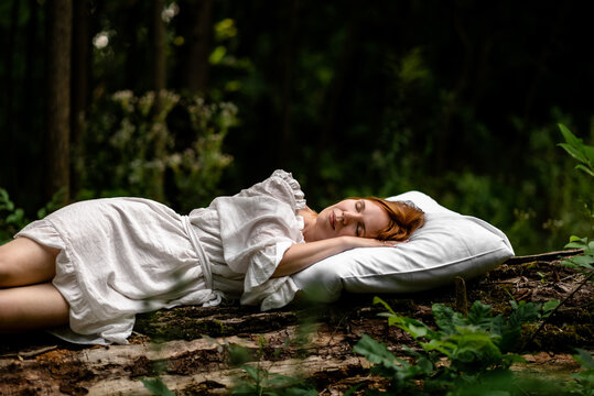 A woman sleeps in the woods on a pillow. Healthy, sound sleep concept. Rest, relaxation in nature.
