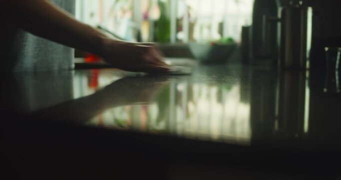 Closeup Slider Shot Of A Woman's Hand Wiping Down A Kitchen Counter.