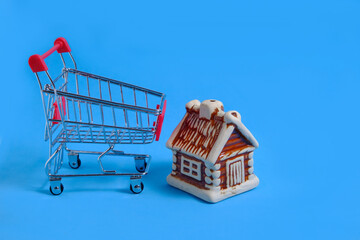House next to a metal shopping cart on a blue background,concept of buying an apartment or house.