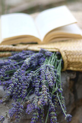 Straw bag filled with fresh lavender flowers and open book. Selective focus.