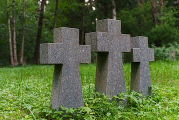 Three stone crosses in a cemetery in the forest.