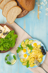 Fototapeta premium Durum pasta, eggs, greens, arugula, proper nutrition, top view on a wooden blue background 