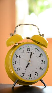 Old retro yellow clock with bells ticking on a desk at home in the morning. Close up and copy space. The vertical position of the video