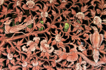 Wooden carved panel of red color with the image of birds flowers and animals