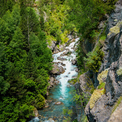 Fototapeta na wymiar Aerial drone view of a waterfall in a river with turquoise water located in a green natural environment in Pyrenees, Spain.