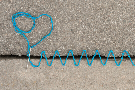 the crack in the asphalt is sewn with colorful threads symbolizing the union of incompatible or illogical things