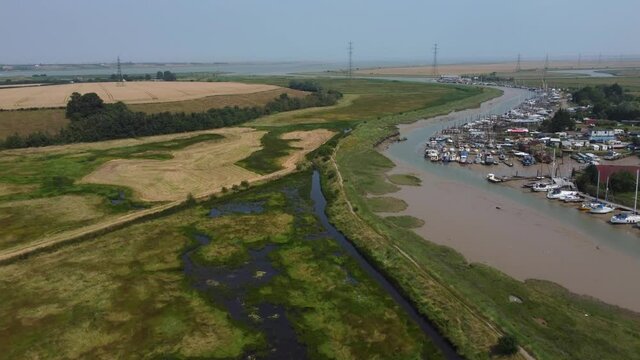 4K drone video flying over marsh land with a stream and boat in the background