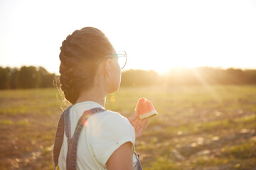 a girl eats a delicious watermelon in the park at sunset