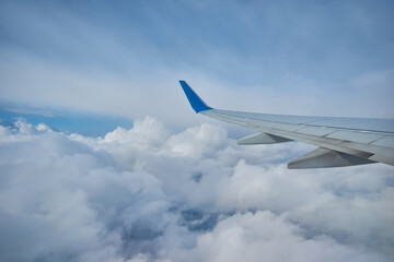 Wing of an airplane flying above the clouds. people looks at the sky from the window of the plane