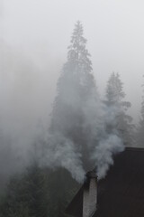 Fototapeta na wymiar summer in the mountains. smoke from the chimney. foggy morning.