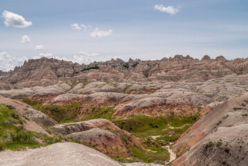 Badlands National Park, SD, USA - June 1, 2008: A bad place to loose a calf is this wirwar of geological maroon-gray upcrops with a bid of green in between, a mountain range in back under blue sky.