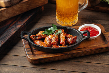 Cast iron plate of fried chicken wings in teriyaki sauce