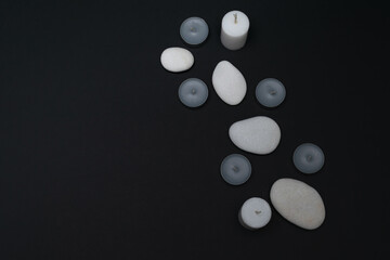 Spa still life with scented candles, stones for beauty treatments on a dark background. Layout, place for text.