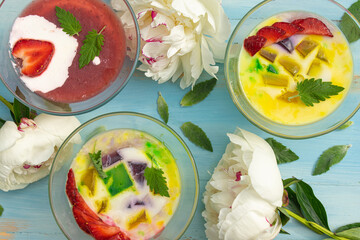 Healthy breakfast of milk jelly with fresh fruit in glass bowls on a rustic blue table. 
