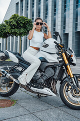 Obraz na płótnie Canvas Trendy female biker sitting on modern motorcycle in city