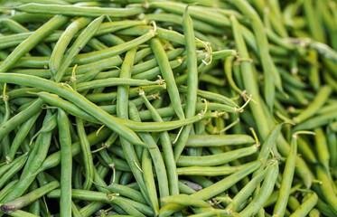 Pile green string beans displayed on food market. Abstract healthy nutrition background - shallow depth of field photo, only few hulls in focus