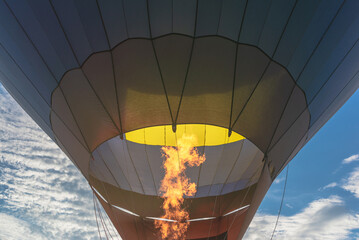 Hot flame from a gas burner light up inside of a hot air balloon at evening.