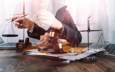Justice and law concept.Male judge in a courtroom with the gavel, working with, computer and docking keyboard, eyeglasses, on table in morning light