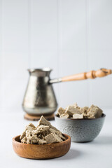 Pieces of halva in bowls and a coffee turk in the background. Oriental sweetness. Copy space.