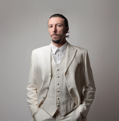 Portrait of an adult Italian mafia boss wearing a white suit against a gray background