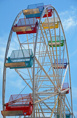 Empty colorful seats of ferris wheel ride. - obrazy, fototapety, plakaty