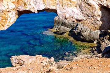 Natural stone arch Kamara Tou Koraka. Another name is Sinner Bridge. Cape Greco National Forest Park on the island of Cyprus. Azure water in the bay of the arch.