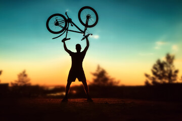 a cool contrast illustration of a man holding a bicycle over his head against the backdrop of the setting sun. Beautiful blurred background. Extreme. bmx. sport.
