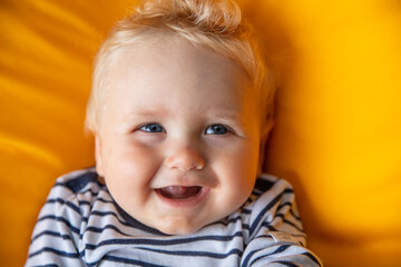 Close up of a cute 9 month old baby boy with blue eyes on a yellow background