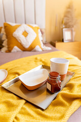 Fototapeta na wymiar Bedroom breakfast, home accents, tray food whit empty coffee mug and marmalade jar in bed yellow blanket angle view