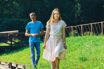 Fototapeta premium A couple in love walks in a summer park by the lake.A woman leaves her man