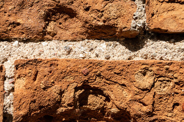 Fragment of an old brick wall with layers of cement. Close-up.