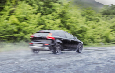 car moves under a downpour on a country road along the forest.