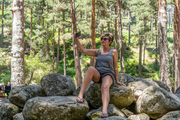 mujer haciendo una videollamada y selfies encima de unas rocas en la montaña rodeada de arboles