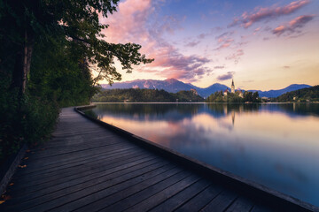 Wooden promenade near lake in mountains at sunset