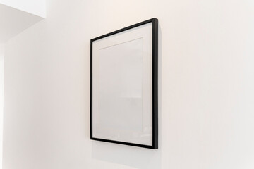 Home decoration, empty black frame, poster, white canvas, mock up on a white wall, living room,...