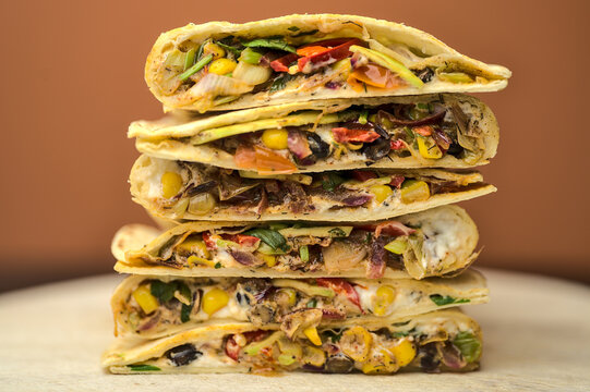 Beautiful Closeup View Of Delicious Creamy Black Bean Mexican Quesadillas With Sweet Corn, Avocado, Red Onion, Chili Pepper And Coriander On Wooden Serving Board. Quesadilla Background