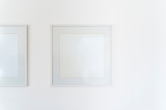 Empty square white frame, poster white canvas mock up on a white wall, living room, template front view, home decoration