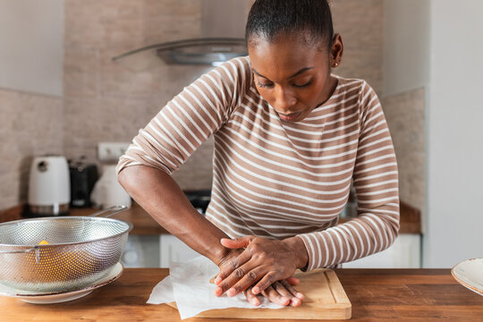 Black woman preparing tostones at table in kitchen