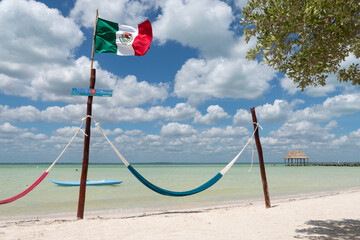Mexican flag blowing in the wind on a caribbean beach encima de una hamaca